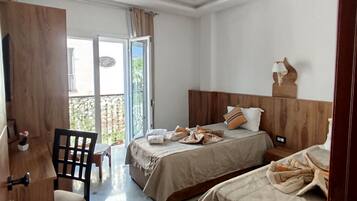 A hotel room with two beds, a desk, and a chair.