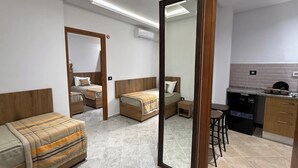 A modern hotel room with two single beds, a sofa, a small kitchen area, and a bathroom. - Dar Farhat Suite Hotel (Tunis)