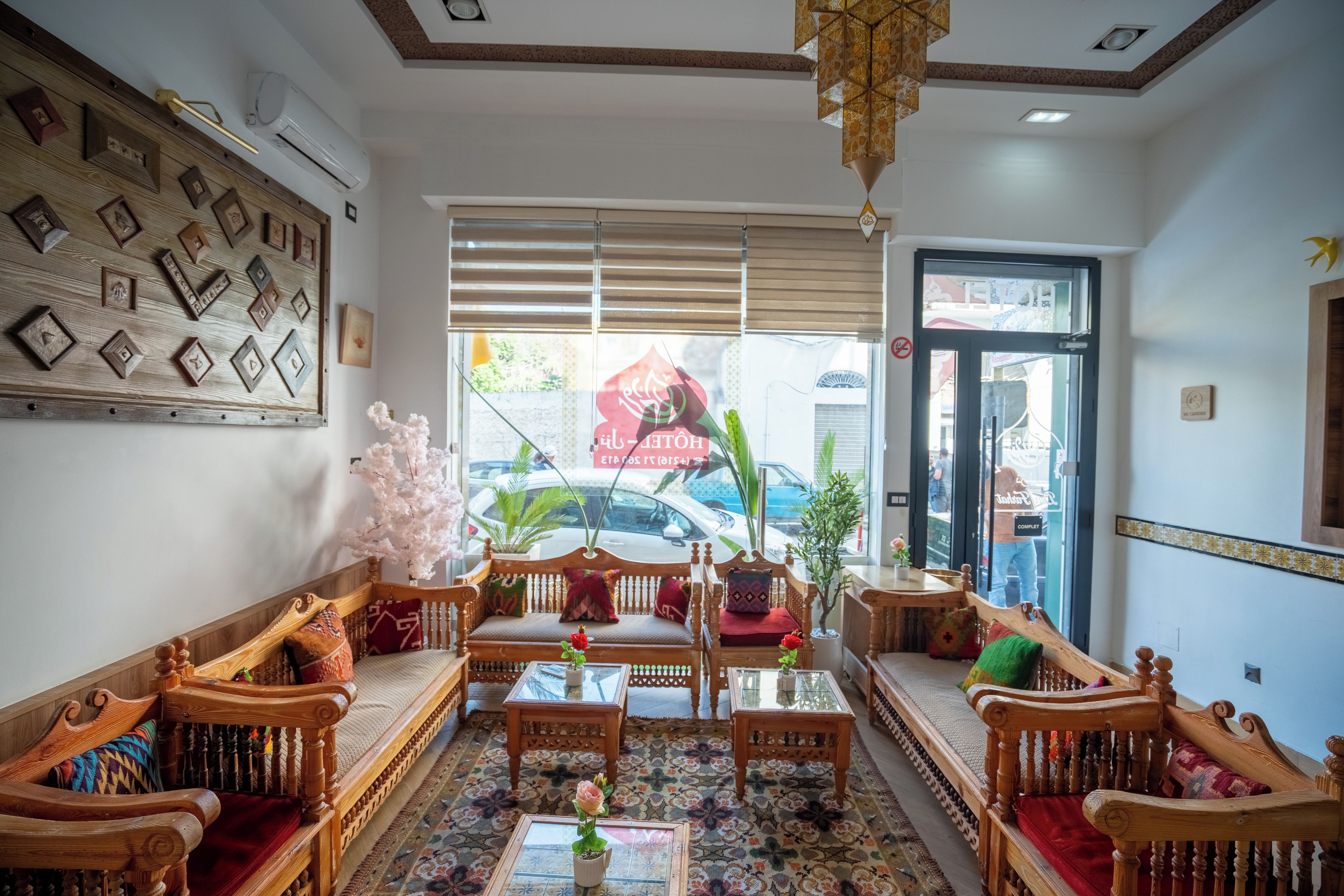A hotel lobby with a traditional wooden sofa set, a glass coffee table, and a patterned rug.