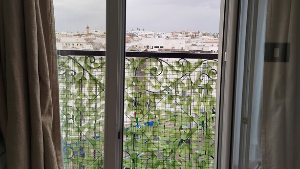 A room with a view through a glass door, a curtain, and a metal gate. - Dar Farhat Suite Hotel (Tunis)