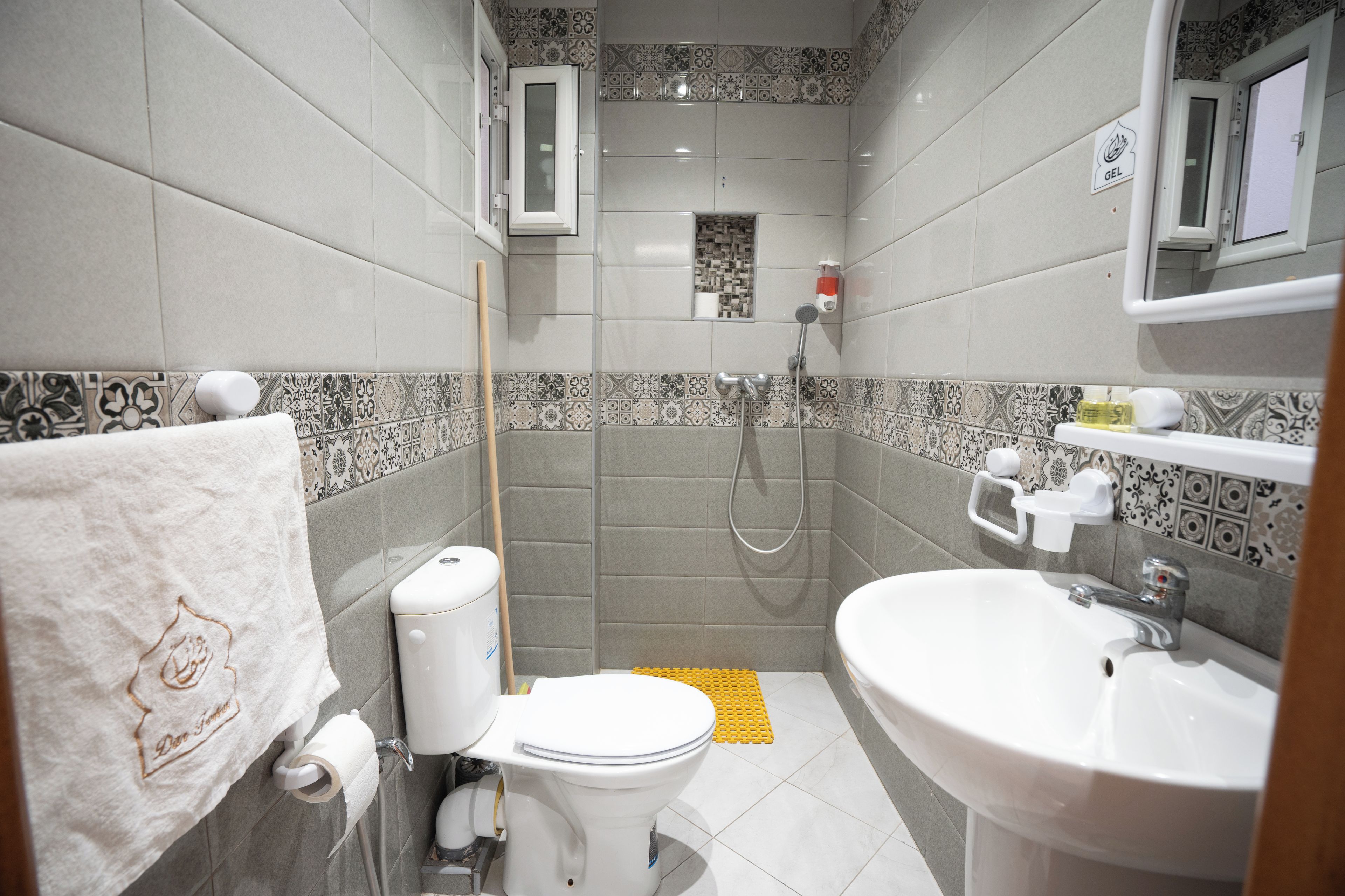 A bathroom with a toilet, sink, shower, and a towel rack.