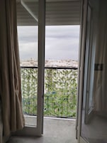 Una habitación con vista a través de un vidrio, una cortina y una reja de metal.