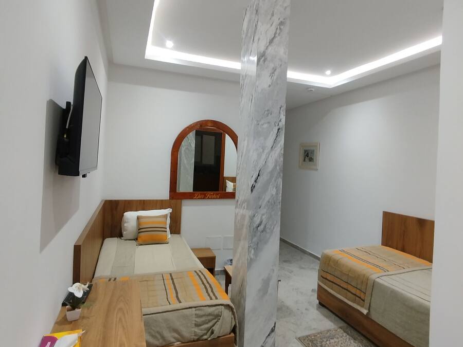Un dormitorio moderno con una cama de madera, un pilar de mármol y un televisor de pantalla plana montado en la pared.