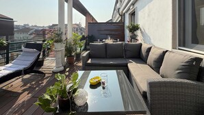 Una terrazza sul tetto con un divano, poltrone e piante in vaso.