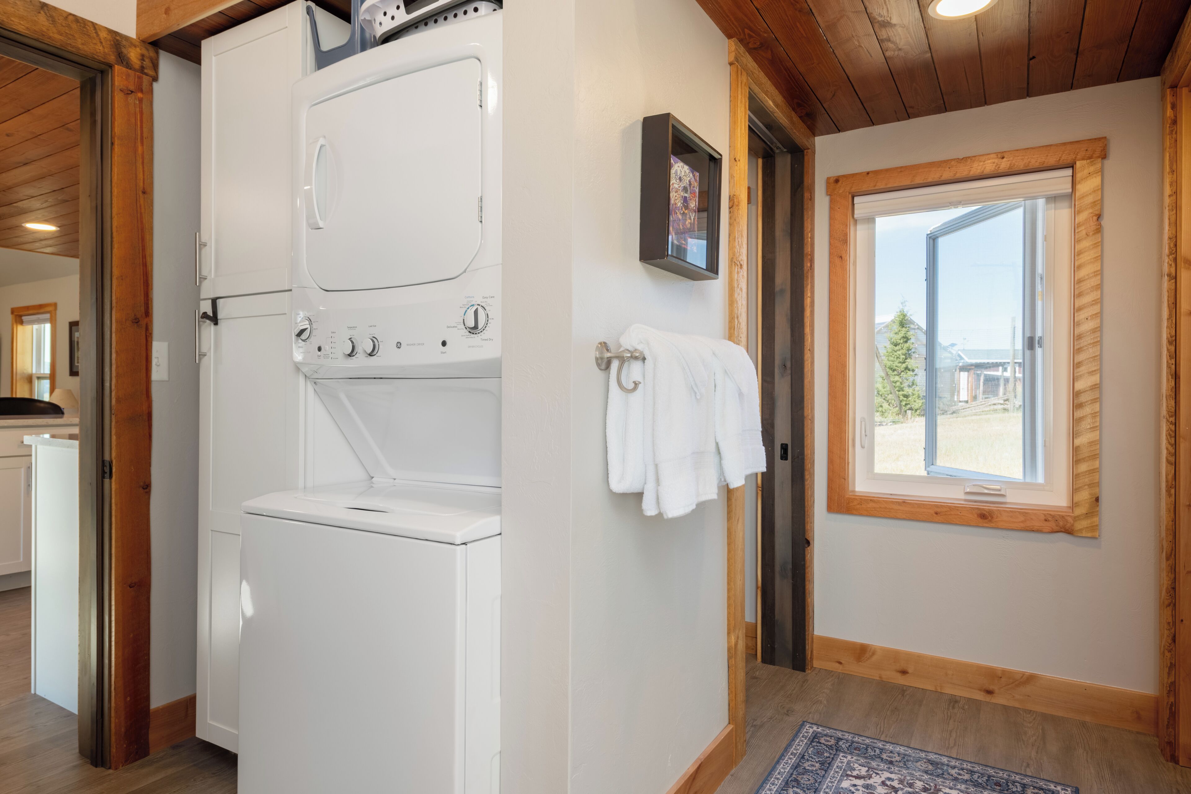 A laundry room with a washer and dryer, a towel rack, and a window with a view of the outside.