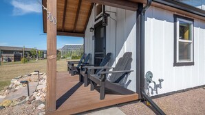 Ein überdachter Außenbereich mit Adirondack-Stühlen und einer Holzterrasse.