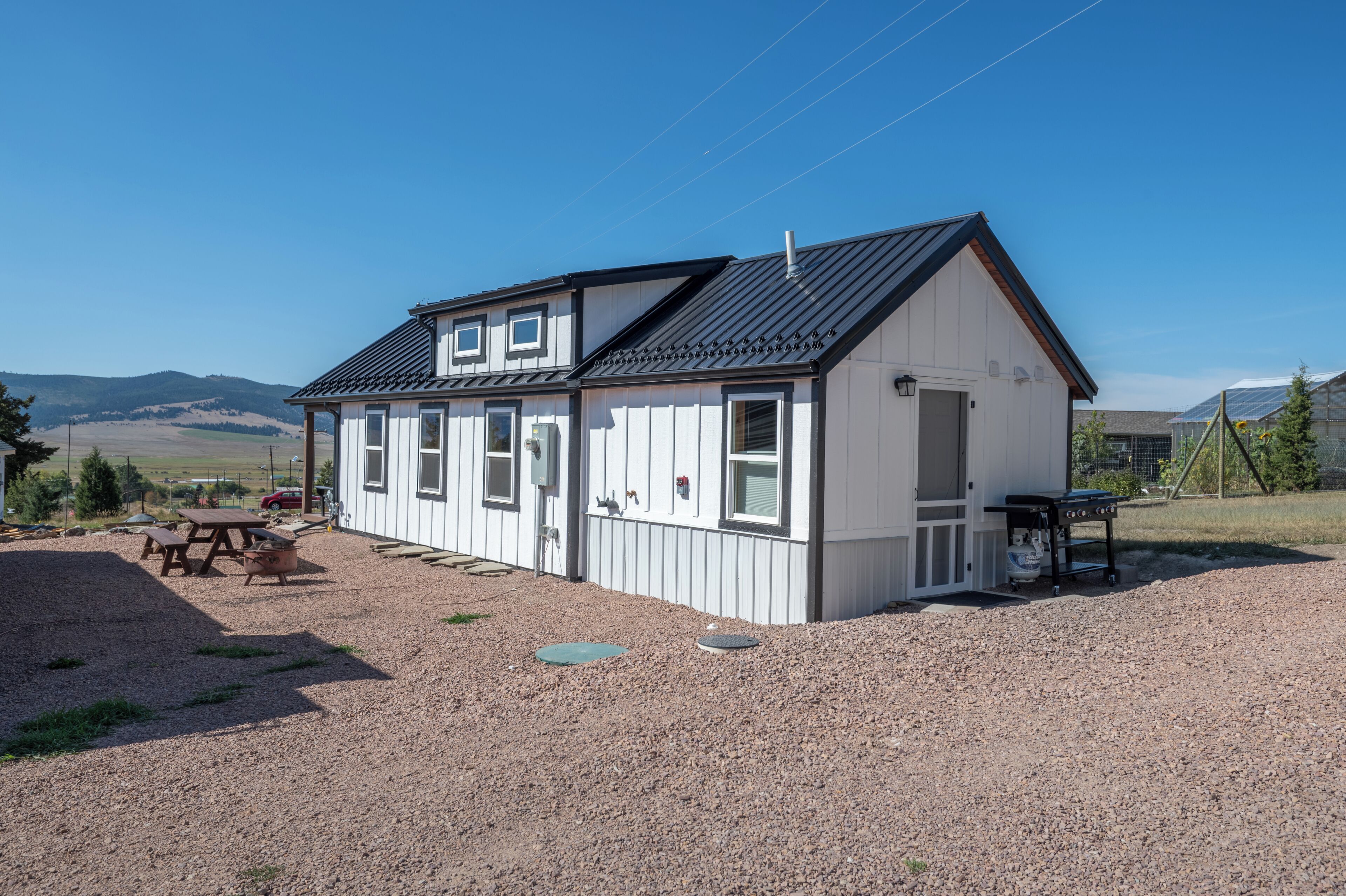 A small, single-story building with a sloped roof, a front porch, and a gravel driveway.