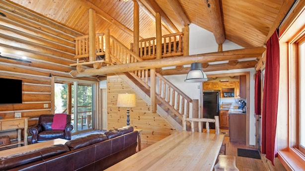 A log cabin interior with a wooden staircase, a dining area, and a kitchen. - Stony Creek Lodge-Famous Rock Creek MT! 4 seasons! (Philipsburg)