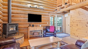 A log cabin interior with a fireplace, leather furniture, and a mounted television. - Stony Creek Lodge-Famous Rock Creek MT! 4 seasons! (Philipsburg)