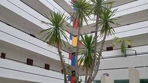 Ein modernes Atrium mit einer zentralen Pflanze, mehreren Etagen und Topfpflanzen.