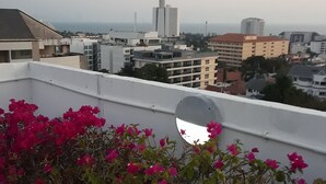 Eine Dachgartenanlage mit Bougainvilleen und Blick auf eine Stadtlandschaft, darunter ein Turm.