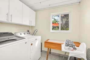 A laundry area with a washing machine, dryer, and a table with a chair.