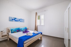 Una camera da letto con un letto, un comodino, una finestra e una porta.