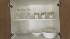 A cabinet with shelves containing wine glasses, bowls, and plates. - Comfortable Getaway for Families & Groups (Byford)