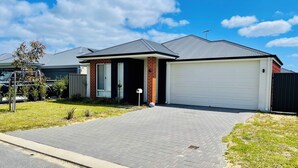 A residential house with a garage, a driveway, and a well-maintained lawn. - Comfortable Getaway for Families & Groups (Byford)