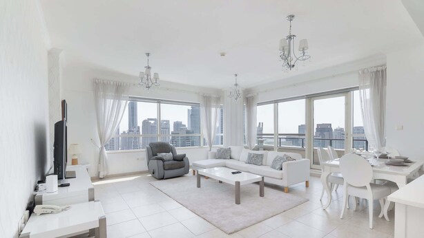 A spacious living room with a sofa, a coffee table, a TV, and a dining area with chairs and a table. - StayShort - Dubai Marina sleeps 4 with Marina Views! (Dubai Marina)