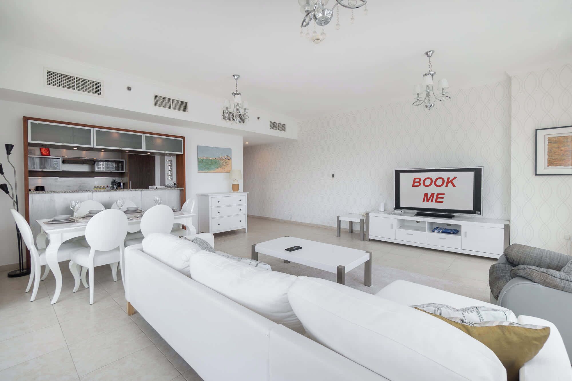 Un salon moderne avec un canapé blanc, une table à manger et un téléviseur.