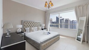 A modern hotel room with a large bed, a nightstand, a desk, a chair, a mirror, and a city view. - StayShort - Dubai Marina sleeps 4 with Marina Views! (Dubai Marina)