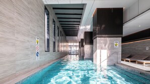 Una piscina interna con acqua cristallina, pareti piastrellate e design moderno.