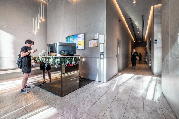 En modern entréhall med en receptionsdisk, en digital skärm och en övervakningskamera.