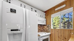 Cozinha compacta com geladeira, micro-ondas e forno.