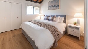 Une chambre à coucher avec un lit, des tables de chevet, une fenêtre et un tableau au mur.