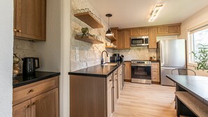 Une cuisine moderne avec des meubles en bois, un pare-feu en pierre et des appareils électroménagers en acier inoxydable.