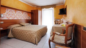 A hotel room with a large bed, a wooden nightstand, a chair, a table with a vase, and a television on the wall. - Stella Alpina Hotel e Ristorante (Druogno)
