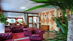 A hotel lobby with red leather sofas, a large mirror, and a wall with a diamond pattern. - Stella Alpina Hotel e Ristorante (Druogno)