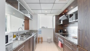 Una cocina moderna con encimeras de granito, electrodomésticos de acero inoxidable y armarios de madera.