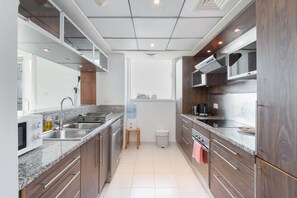 A modern kitchen with granite countertops, stainless steel appliances, and wooden cabinets. - Dubai Marina Sleeps 4 With Marina Views (Dubai)