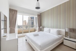 A modern hotel room with a large bed, a bedside table with a lamp, a window with curtains, and a view of the cityscape. - Dubai Marina Sleeps 4 With Marina Views (Dubai)