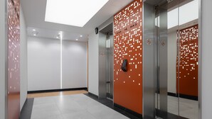 Un ascenseur moderne doté d’écrans numériques et d’un mur orné de motifs géométriques.