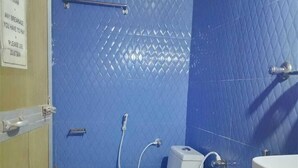 Ein kleines Badezimmer mit blauen Fliesen, einer weißen Toilette, einem Waschbecken und einem an der Wand angelehnten Mopp.