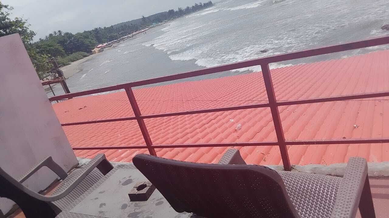 A balcony with a red roof overlooking a beach.