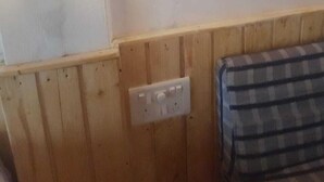 Ein Zimmer mit Holzwand, Steckdose und einem Bett mit Überwurf.