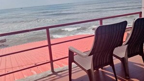 Ein Balkon mit zwei Korbstühlen, der auf das Meer ausgerichtet ist.