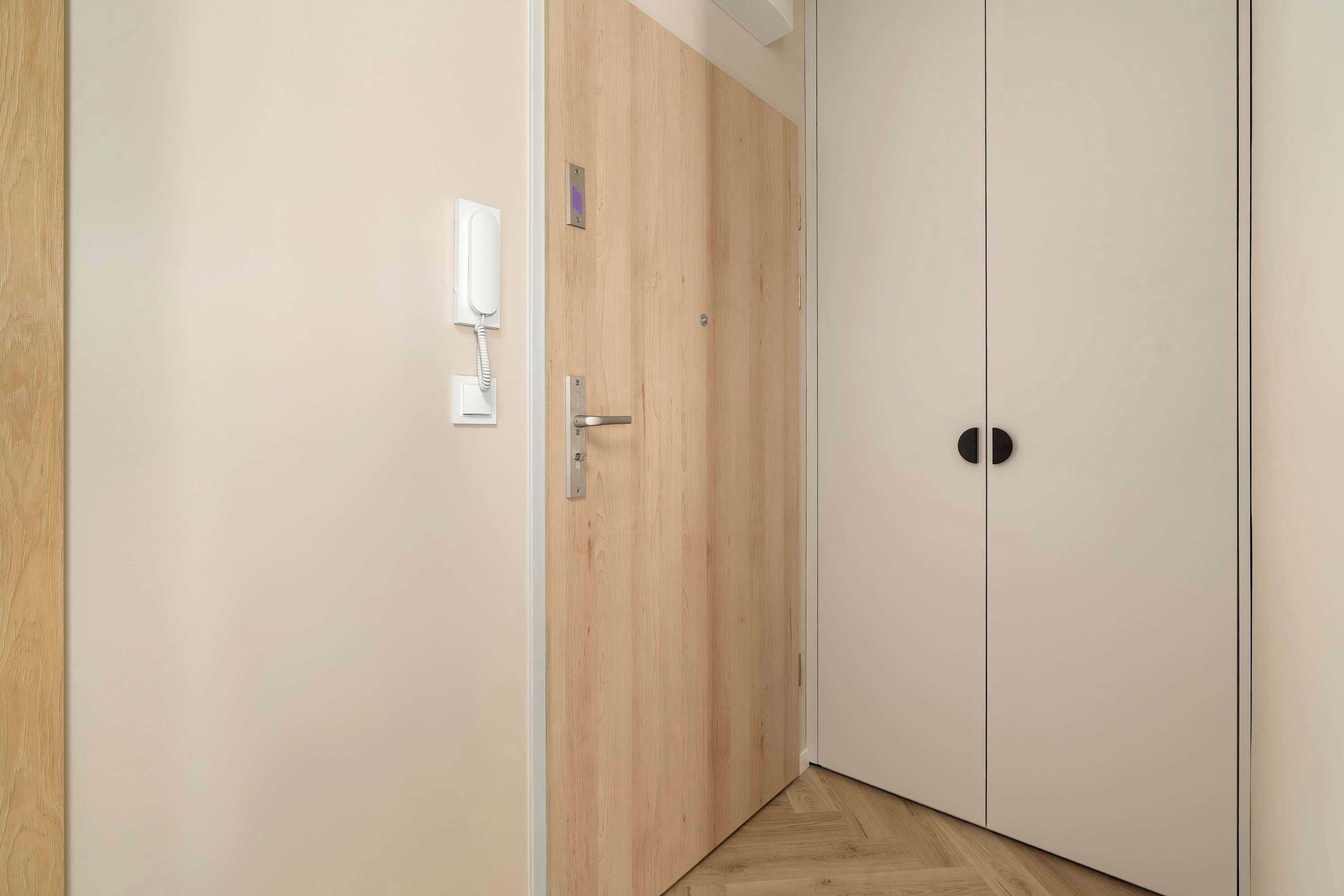 A hallway with a wooden door and a white wall.