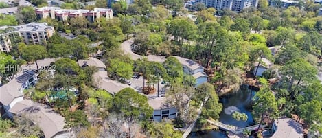 An aerial view of a resort area with multiple buildings, a body of water, and a beach in the background.
