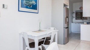 Een moderne keuken met een roestvrijstalen koelkast, witte kasten en een klein aanrecht met spoelbak.