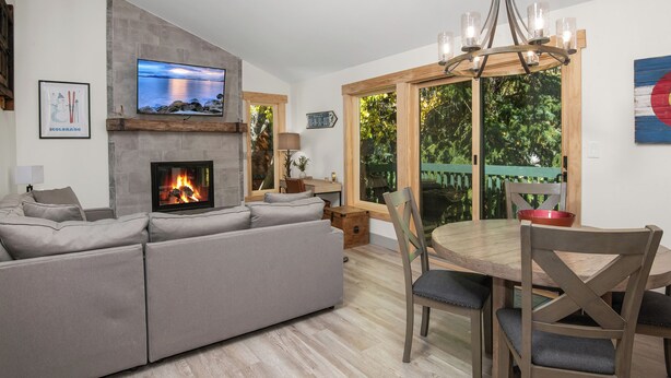 Un salon doté d’une cheminée, d’un téléviseur et d’un coin repas avec des meubles en bois.
