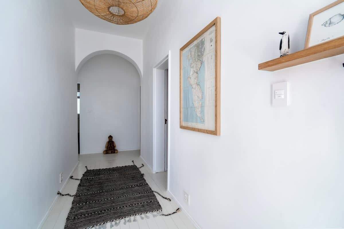 A hallway with white walls, a wooden ceiling, a map, and a shelf with a penguin figurine.