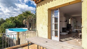 A patio with a wooden table and chairs, a swimming pool, and a view of a house with a door leading to an interior space. - A/C House 4br/10p With Pool - 40 min From Cannes (Le Tignet)