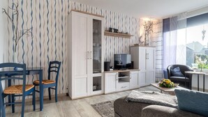 A modern living room with a dining area, a sofa, a TV, and a bookshelf. - Ferienhaus in Busum, 6 Persons (Büsum)