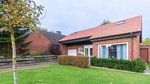 A residential building with a brick facade, a red-tiled roof, and a well-maintained lawn. - Ferienhaus in Busum, 6 Persons (Büsum)