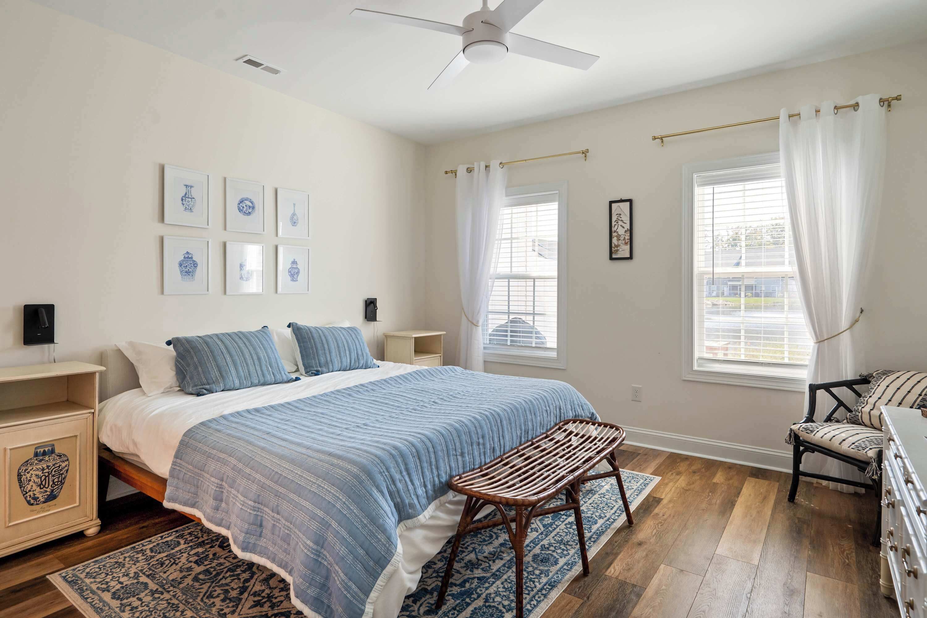 A bedroom with a bed, bedside tables, a bench, and a window with curtains.
