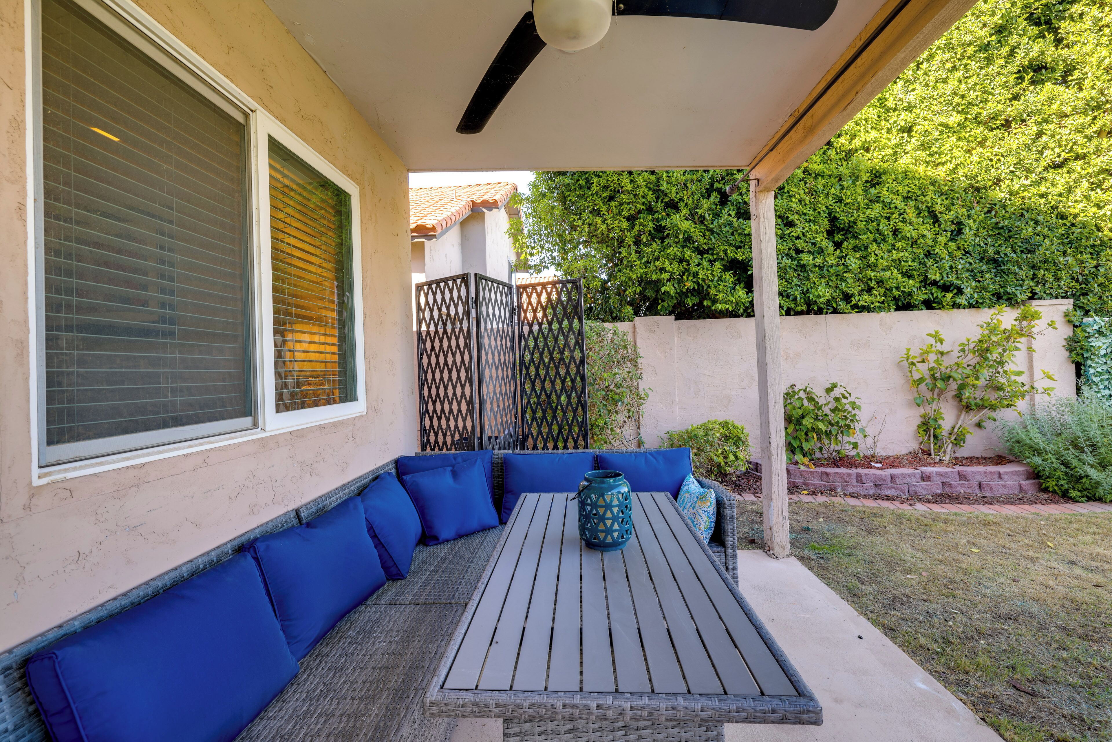 A covered patio with a table and blue cushioned seating.