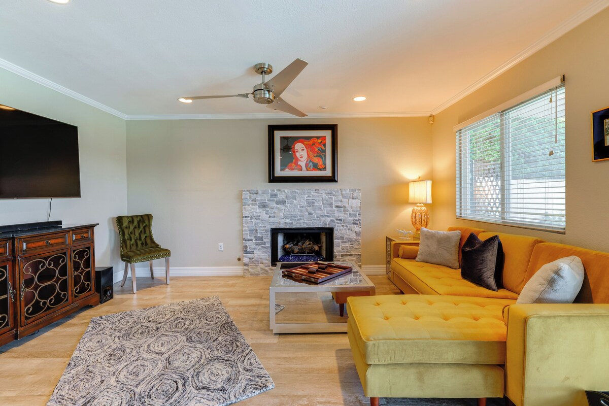 A living room with a fireplace, a sofa, a coffee table, a TV, and a ceiling fan.