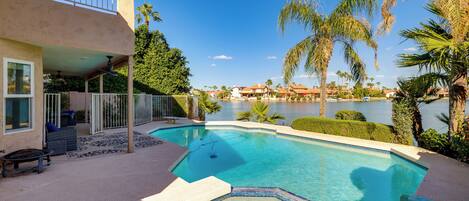 A swimming pool with a view of a lake and palm trees, surrounded by a building with a balcony.