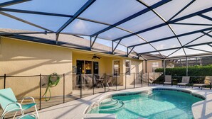 A covered outdoor swimming pool with a ceiling structure, chairs, and a hose.
